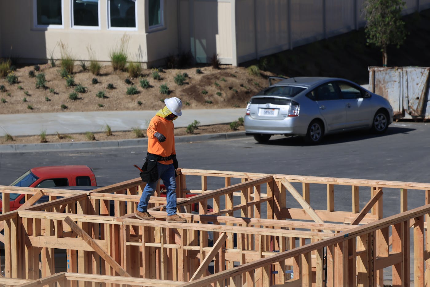 Construction worker in safety gear on wooden framing at a residential build site