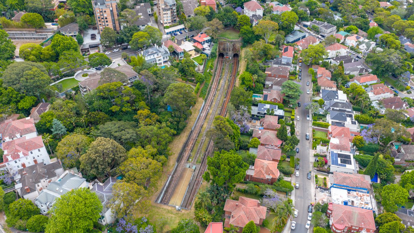 Aerial image of a Sydney suburb with green trees, residential houses and train tracks