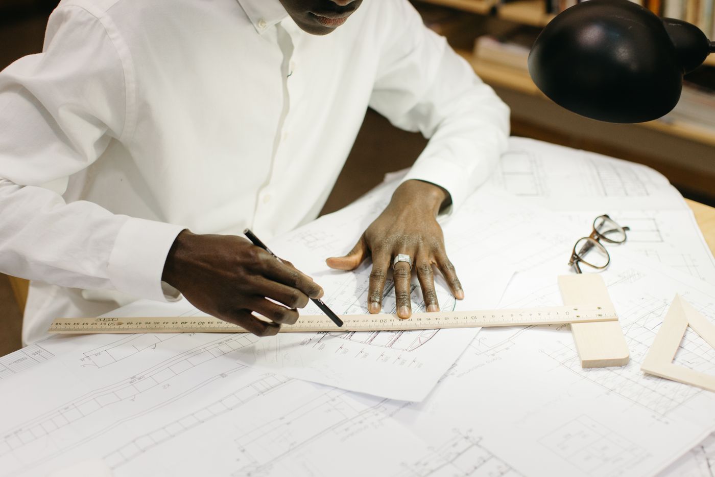 Architect working on blueprints and design documents at a well-lit office desk