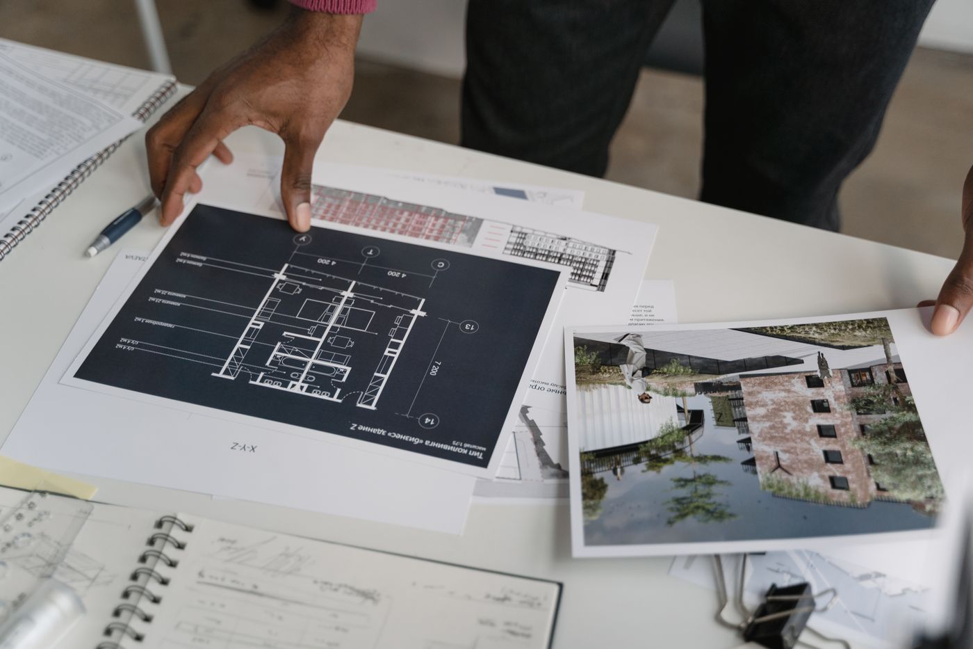 Architect hands reviewing building blueprints and documentation at a desk