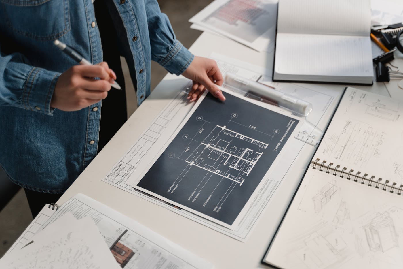 Architect reviewing duplex floor plans and engineering drawings on a desk