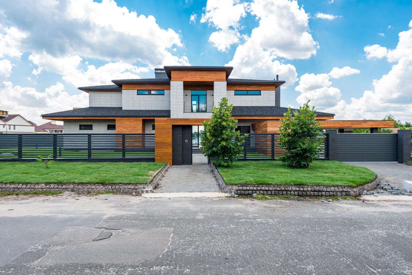 Facade of contemporary luxury villa with lawn and green trees under blue sky