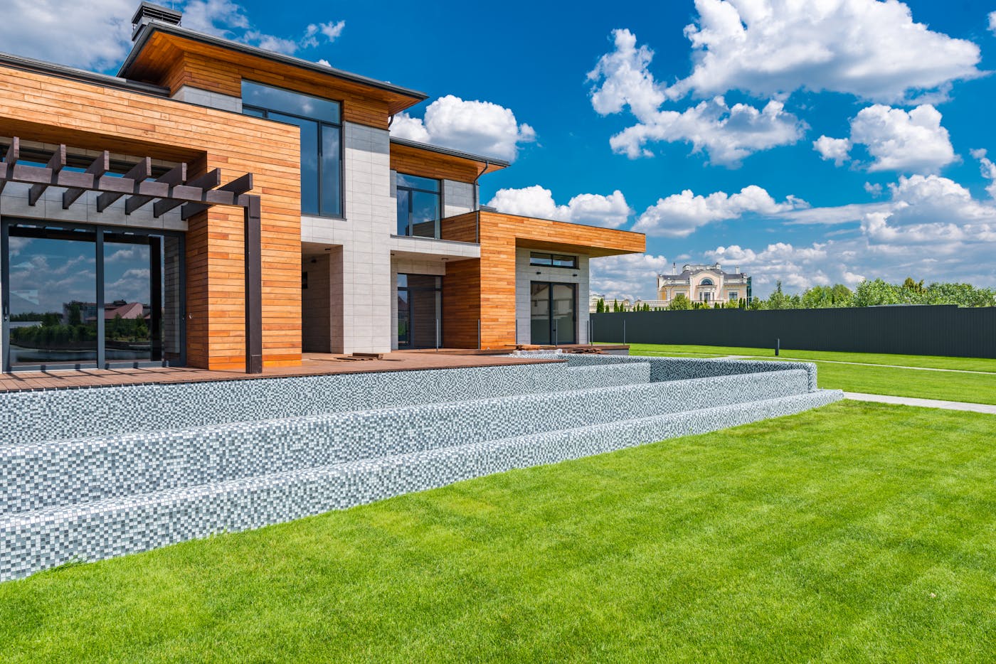 Contemporary architectural home with panoramic windows and green lawn under a blue sky