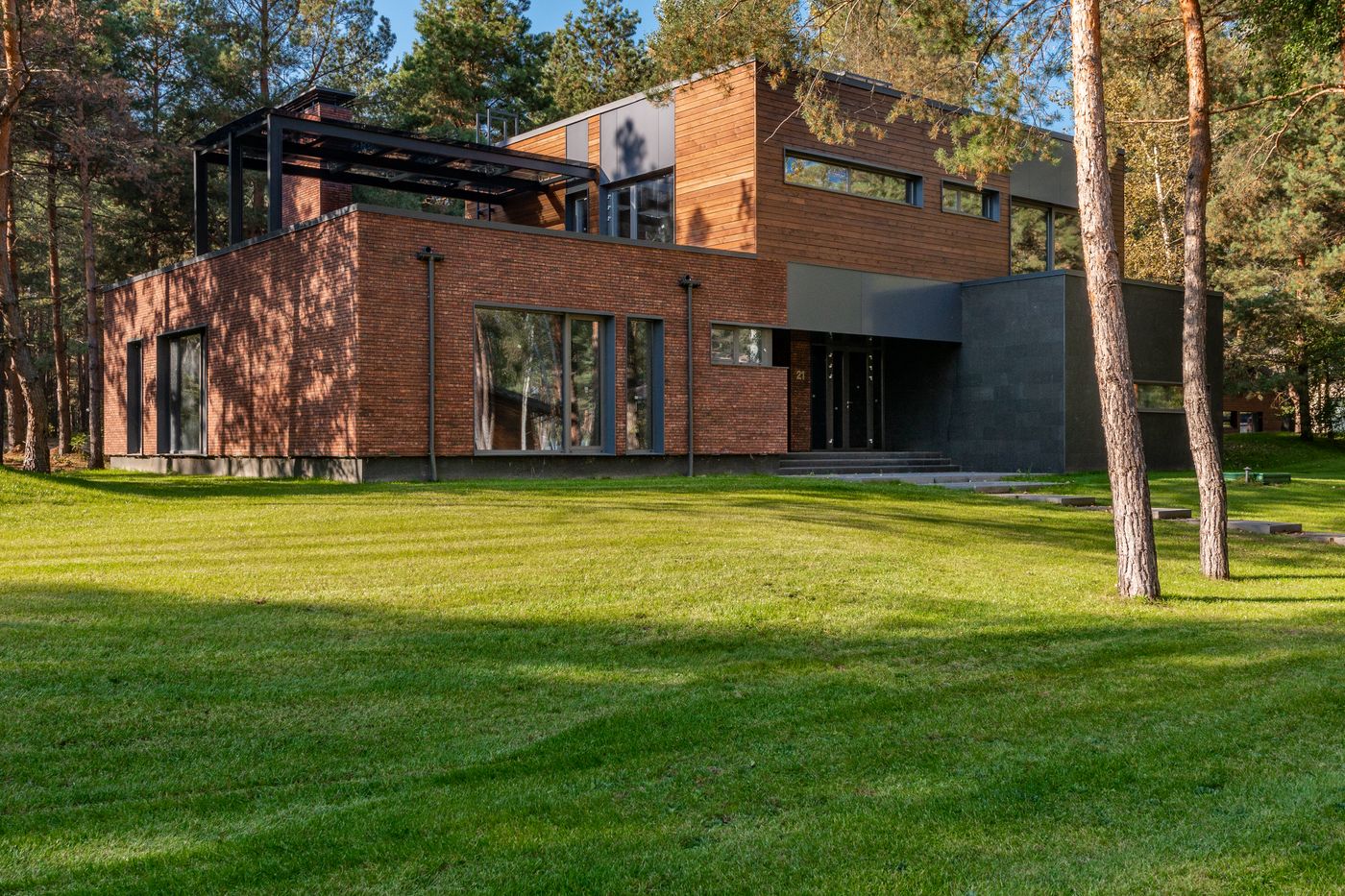 Contemporary custom home with large windows set among established garden greenery