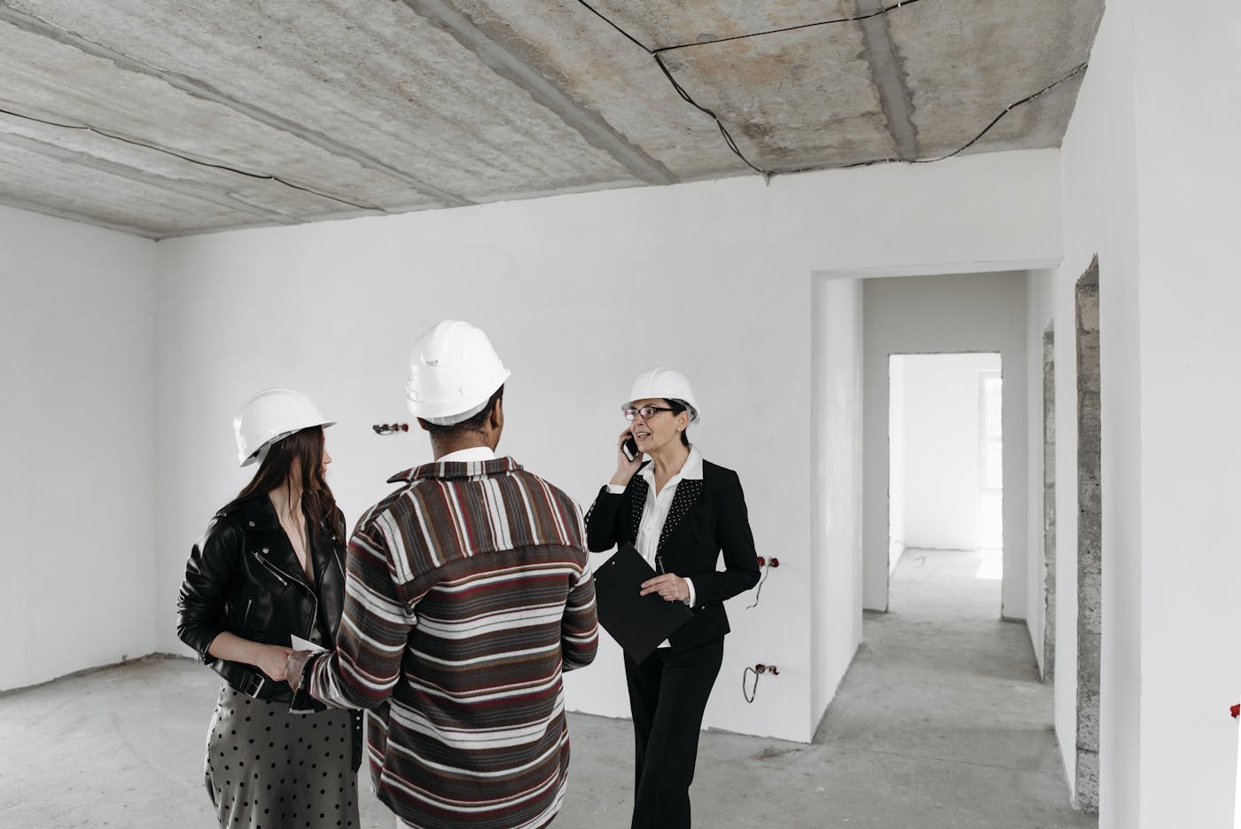Real estate consultant discussing floor plans with clients inside a home under construction