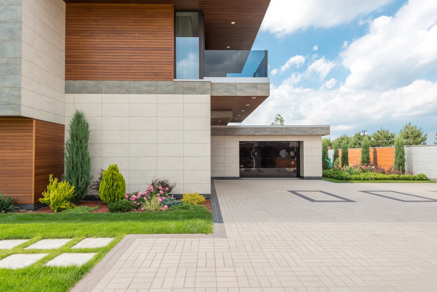Modern minimalist home exterior with spacious driveway and landscaped garden under blue sky
