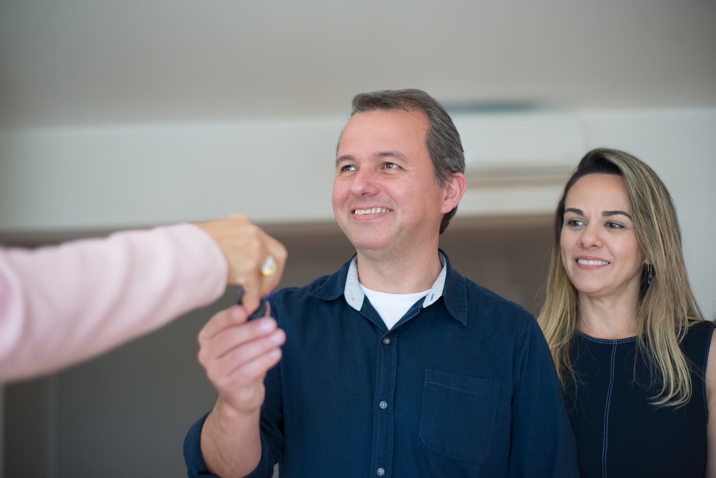 Smiling couple receiving house keys at handover of their new Sydney home