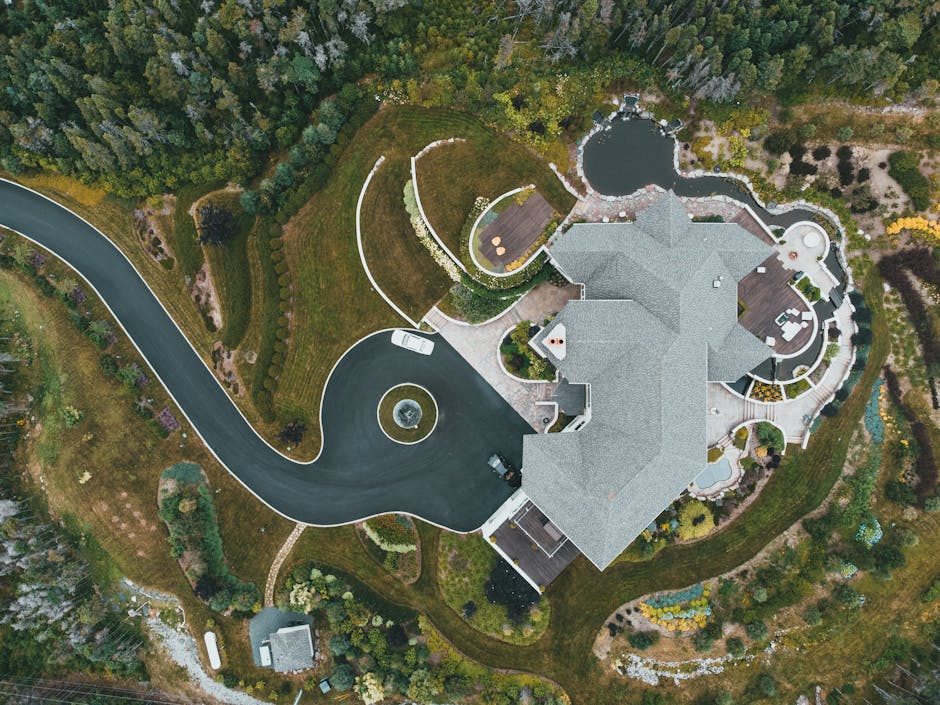 Aerial view of a luxury custom home with manicured gardens and pool