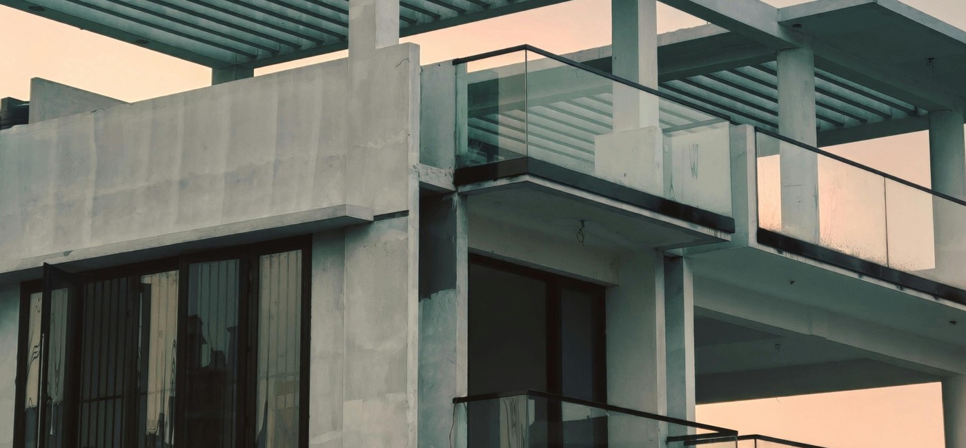 Modern double storey home under construction showing glass balustrades and pergola structure